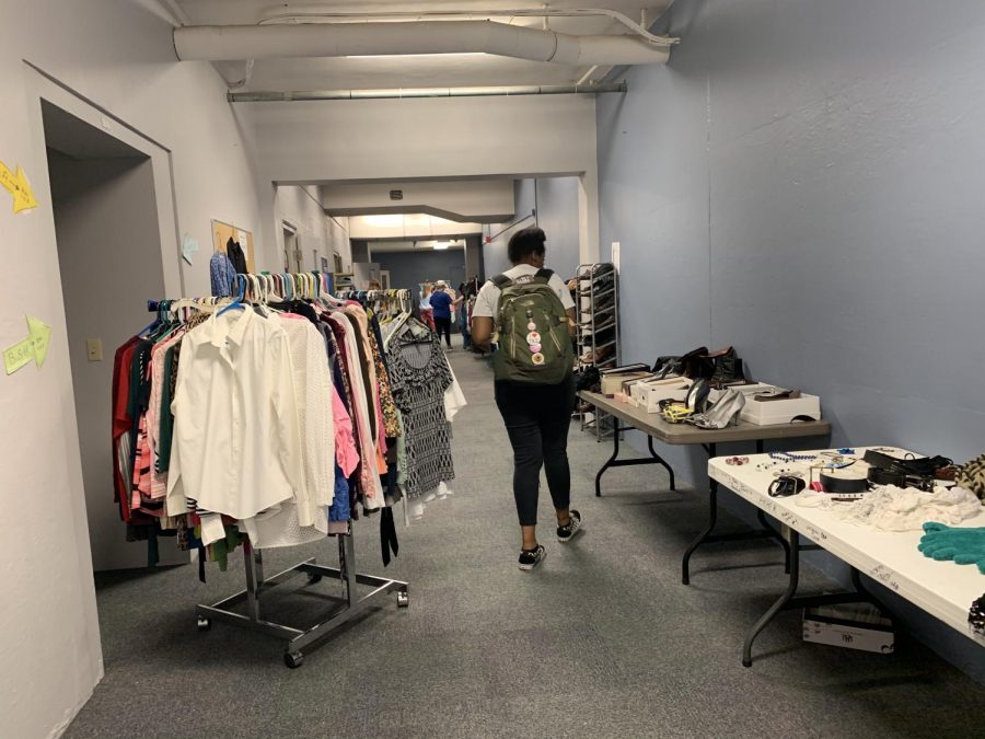 A student walking through the tables of accessories and racks of clothes.