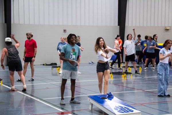 Students playing cornhole in the Mabee Center Gym
